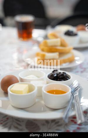 Un gran numero di piatti per la colazione per bambini a scuola o dipendenti di aziende. Su un piatto di uova, miele, formaggio e formaggio fresco Foto Stock