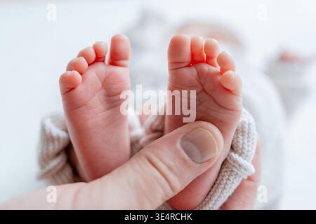 Interazione dei piedi del bambino con le mani degli adulti. Concetto di connessione, protezione e genitorialità. Foto Stock