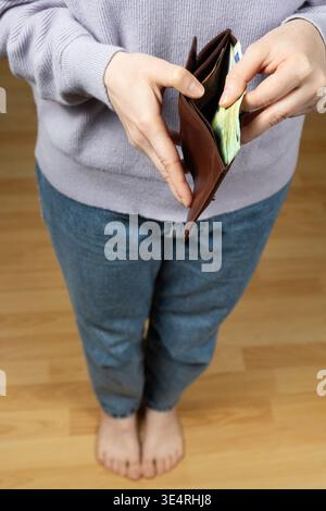 Donna che controlla banconote di carta nel portafoglio marrone da vicino Foto Stock