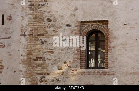 Vecchie pareti in mattoni con finestre ad arco, dettagli architettonici medievali e sfondo testurizzato Foto Stock
