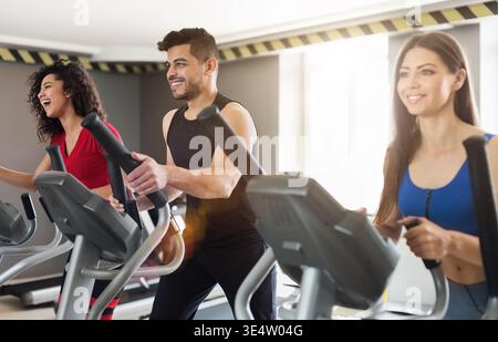 Giovani che si allenano con il cross-trainer in palestra Foto Stock