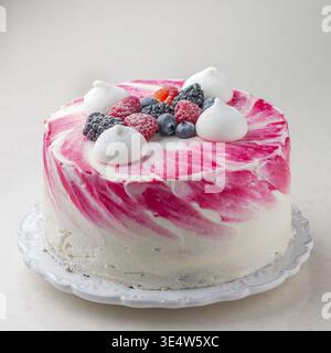 Cibo, deliziosa mousse cake fatta in casa, glassata con cioccolato bianco, decorata con mirtilli, lamponi, more, meringa e zucchero a velo. Foto Stock