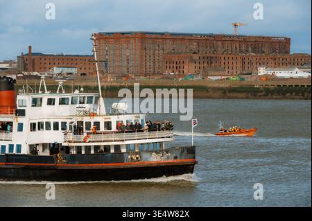Un traghetto passeggeri, il Royal Iris, e una scialuppa di salvataggio navigano sul fiume Mersey a Liverpool, con il Tobacco Warehouse sullo sfondo. Foto Stock