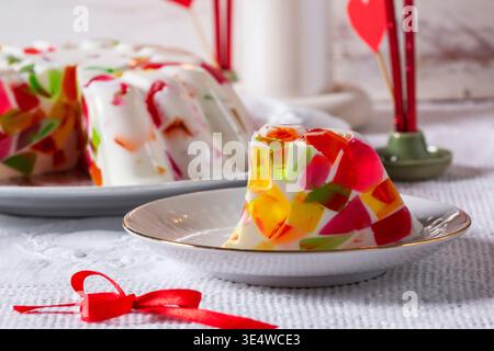 Una torta alla panna con pezzetti di gelatina di diversi colori su uno sfondo chiaro. Dessert di San Valentino. Foto Stock