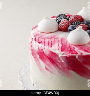 Cibo, deliziosa mousse cake fatta in casa, glassata con cioccolato bianco, decorata con mirtilli, lamponi, more, meringa e zucchero a velo. Foto Stock