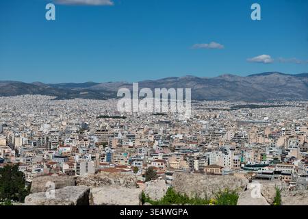ATENE, GRECIA - 18 FEBBRAIO 2026: Vista panoramica ad alto angolo del fitto paesaggio urbano di Atene dall'Acropoli sotto un cielo nuvoloso blu. Foto Stock