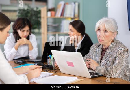Donna anziana seduta stanca e triste alla scrivania dell'ufficio Foto Stock