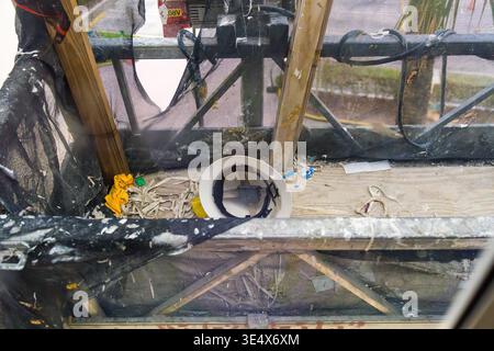 Un elmetto di sicurezza bianco e un panno per la pulizia giallo si trovano sul pavimento di legno di una piattaforma in metallo sospesa utilizzata per lavori su piani alti. Foto Stock
