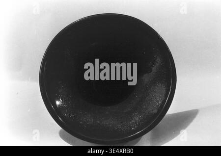 Sloviansk, anni '1960, armature-Insulator Plant (AIZ) - Una macro vista dall'alto verso il basso di un isolante elettrico in ceramica difettoso che mostra gravi imperfezioni di smalto. La fotografia d'archivio rivela chiaramente una superficie macchiata e irregolare in cui il rivestimento industriale scuro non si è asciugato correttamente durante la cottura. Questo documento storico illustra i rigorosi standard di controllo della qualità e le sfide tecniche della produzione di porcellana sovietica della metà del secolo, preservando la realtà dell'industria pesante nel pacifico Donbas. Foto Stock