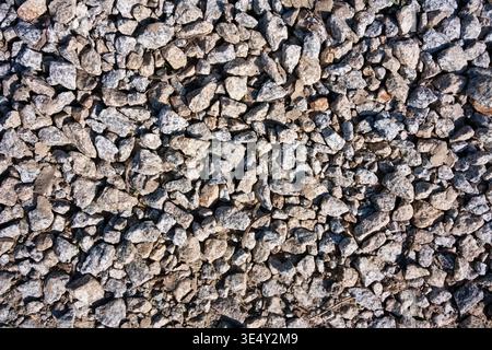 Vista dall'alto delle pietre di granito frantumate e della trama di ghiaia grigia sul terreno Foto Stock