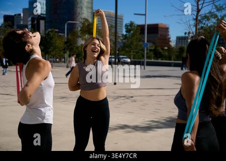 Donne di gruppo che si allenano all'aperto utilizzando bande di resistenza Foto Stock