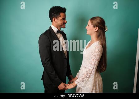 Coppia interrazziale che celebra il giorno del matrimonio tenendosi per mano Foto Stock