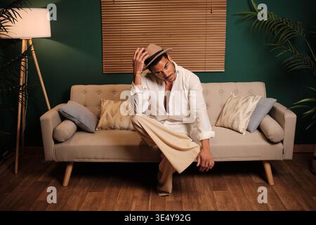 Uomo elegante seduto su un divano che posa con sicurezza in interni moderni Foto Stock