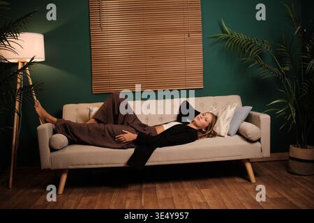 Donna che si rilassa sul divano, che si rilassa a casa Foto Stock