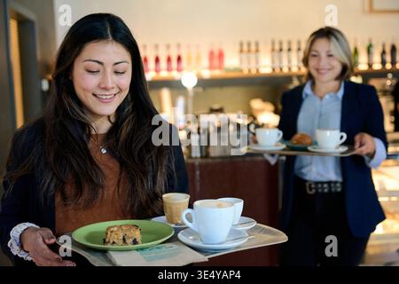 Donna sorridente che riceve caffè e pasticcini dal barista Foto Stock