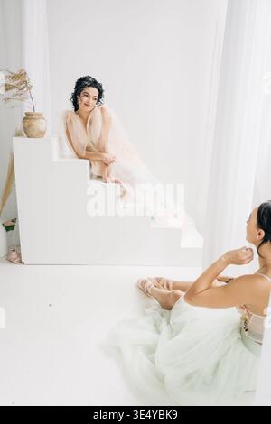 Due ballerine sedute su gradini e pavimento Foto Stock