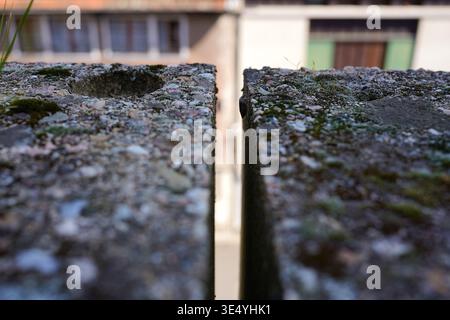 Stretto spazio verticale tra blocchi di calcestruzzo intemprati con sfondo urbano sfocato Foto Stock