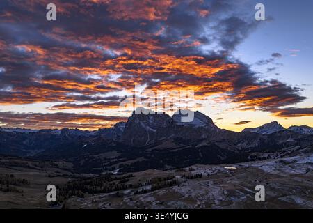 Veduta aerea di una spettacolare alba che illumina il Sassolungo e Sassopiatto nelle Dolomiti, gettando lunghe ombre nel tranquillo paesaggio dell'Alpe di Foto Stock