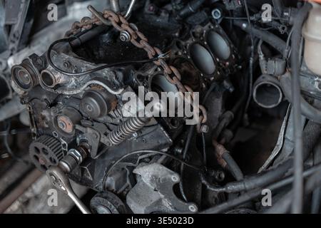 Motore sporco auto smontato primo piano su parti del motore e testata in garage Foto Stock