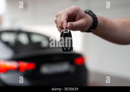 la mano dell'uomo tiene le chiavi della macchina e le consegna all'acquirente. Noleggia un'auto. Prova su strada Foto Stock