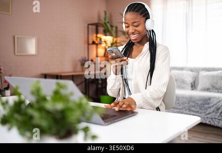 Giovane donna afroamericana che ama la musica e lavora da casa Foto Stock