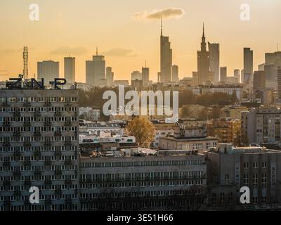 Veduta aerea di un vasto paesaggio urbano punteggiato da moderni grattacieli che attraversano la foschia dorata, in contrasto con gli edifici più vecchi sottostanti, Foto Stock