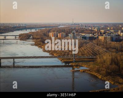 Vista aerea del fiume Vistola che scorre sotto il ponte Swietokrzyski, riflettendo una luce soffusa e dorata sullo skyline di Varsavia, Varsavia, Polonia. Foto Stock
