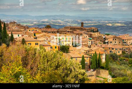 Città collinare di Montalcino in Toscana, Italia, che mostra edifici storici e tetti di terracotta contro l'iconica campagna ondulata, Italia. Foto Stock