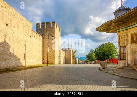 Le mura di pietra storiche del Palazzo Topkapi vicino all'ingresso del Portale Imperiale, con la Fontana del Sultano Ahmed III davanti, a Istanbul, Turchia. Foto Stock