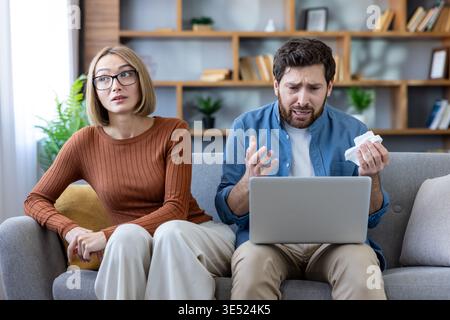 La coppia interessata sta partecipando a una sessione di terapia online via laptop a casa, discutendo problemi di relazione con uno specialista di salute mentale remoto per guida e supporto Foto Stock
