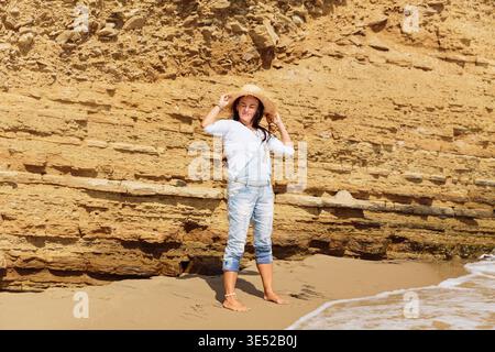 Donna sicura di sé che si gode la luce del sole sulla scogliera costiera di arenaria in estate. Foto Stock