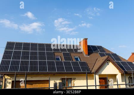 Tetto moderno coperto da pannelli solari. Casa residenziale con pannelli solari sul tetto sotto un cielo azzurro, che rappresentano energia pulita, bollette più basse Foto Stock