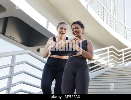 Due donne più grandi che guardano lo smartwatch mentre scendono sulle scale Foto Stock