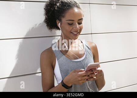 Giovane donna che controlla l'app sul cellulare dopo l'allenamento Foto Stock