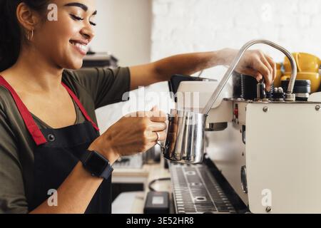 Primo piano di una barista che prepara il latte montato con una caraffa per la schiuma Foto Stock