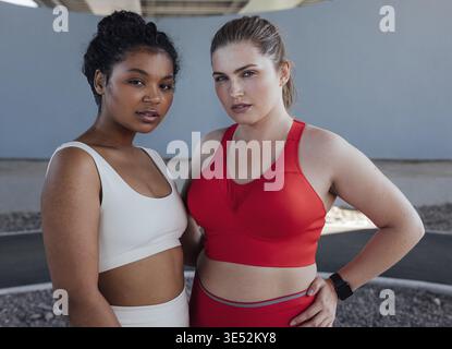 Ritratto di due giovani donne più grandi in abbigliamento sportivo. Due donne di diverse etnie stanno insieme dopo l'allenamento all'aperto Foto Stock