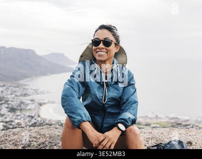 Allegro turista in occhiali da sole seduti su una cima della montagna Foto Stock