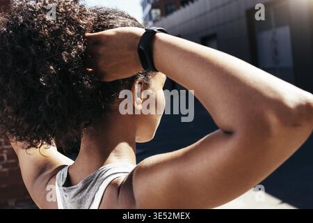 Primo piano di una giovane donna che si fa i capelli, vista posteriore Foto Stock