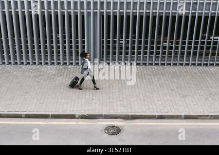 Angolo di alta vista di imprenditrice a piedi con la valigia vicino parcheggio garage Foto Stock