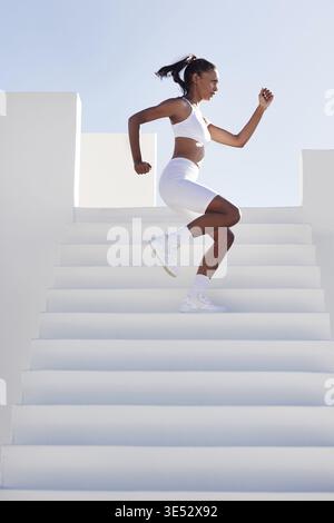 Vista laterale del riscaldamento femminile sottile sulle scale. Donna che lavora sulle scale Foto Stock