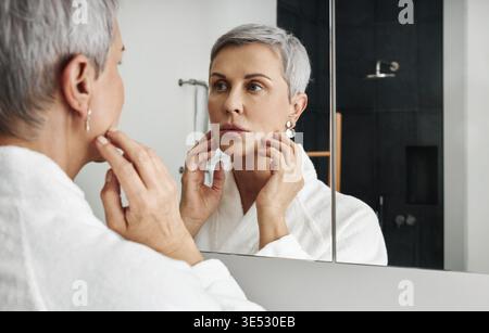 Donna matura con capelli grigi corti che toccano il viso Foto Stock