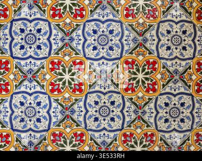 Un dettagliato primo piano delle tradizionali piastrelle azulejo portoghesi con un motivo floreale blu, rosso e giallo su sfondo bianco Foto Stock