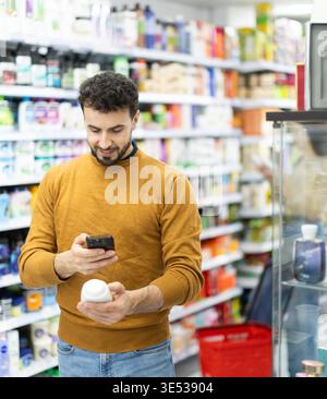 Giovane che scansiona il codice QR sui prodotti per la cura Foto Stock