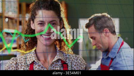 Donna sorridente che indossa un top a motivi geometrici e un grembiule rosso che lavora in negozio con scaffali, grafici verdi, griglia Foto Stock