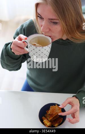 Primo piano di una donna che assaggia favo, dessert naturale e concetto di nutrizione benessere a casa. Foto Stock