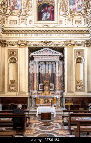 Uomo anziano solitario che prega davanti all'altare all'interno della Basilica di Santa Maria in Trastevere a Roma Foto Stock