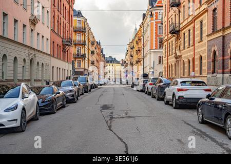 Una vista a livello della strada di una strada stretta costeggiata da colorati appartamenti tradizionali e auto parcheggiate a Stoccolma, Svezia. Foto Stock