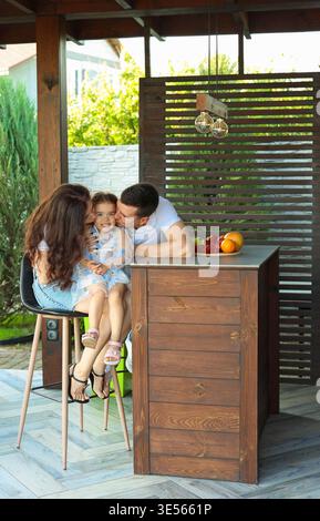 papà e mamma baciano la loro figlia Foto Stock