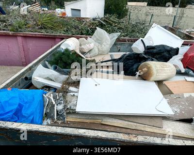 un grande contenitore in un impianto di riciclaggio contiene rifiuti ingombranti, compresi mobili rotti, sacchetti pieni di detriti, tubi e altri d Foto Stock