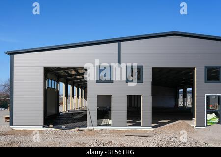 Moderno edificio industriale in costruzione con facciata a pannelli sandwich in metallo e grandi aperture Foto Stock